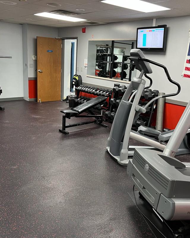 Wide view of room showing dumbells, step machine and part of treadmill