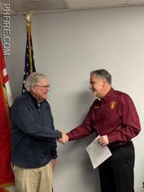 Board president Jim Rebecca congratulating new trustee Bill McDonald after administering the oath of office