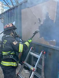A high school intern using an axe to break out a window